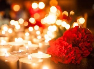 Зажжённые свечи и красные гвоздики в память жертв политических репрессий